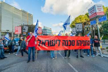 Hayfa, İsrail - 26 Nisan 2025: Çeşitli tabelaları ve bayrakları olan insanlar, savaşın sona ermesi, rehine anlaşmasının tamamlanması ve yeni seçimlerin başlatılması için düzenlenen protesto mitingine katıldılar. Hayfa, İsrail