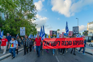 Hayfa, İsrail - 26 Nisan 2025: Çeşitli tabelaları ve bayrakları olan insanlar, savaşın sona ermesi, rehine anlaşmasının tamamlanması ve yeni seçimlerin başlatılması için düzenlenen protesto mitingine katıldılar. Hayfa, İsrail