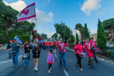 Hayfa, İsrail - 26 Nisan 2025: İnsanlar savaşın sona ermesi, rehine anlaşmasının tamamlanması ve yeni seçimler çağrısında bulunan bir protesto yürüyüşüne (Pembe Cephe Grubu) katılıyor. Hayfa, İsrail