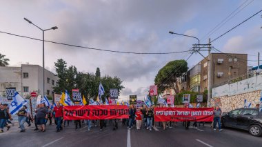 Hayfa, İsrail - 26 Nisan 2025: Çeşitli tabelaları ve bayrakları olan insanlar, savaşın sona ermesi, rehine anlaşmasının tamamlanması ve yeni seçimlerin başlatılması için düzenlenen protesto mitingine katıldılar. Hayfa, İsrail