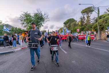 Hayfa, İsrail - 26 Nisan 2025: Çeşitli tabelaları ve bayrakları olan insanlar, savaşın sona ermesi, rehine anlaşmasının tamamlanması ve yeni seçimlerin başlatılması için düzenlenen protesto mitingine katıldılar. Hayfa, İsrail