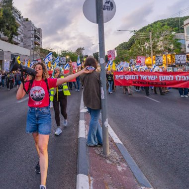 Hayfa, İsrail - 26 Nisan 2025: Çeşitli tabelaları ve bayrakları olan insanlar, savaşın sona ermesi, rehine anlaşmasının tamamlanması ve yeni seçimlerin başlatılması için düzenlenen protesto mitingine katıldılar. Hayfa, İsrail