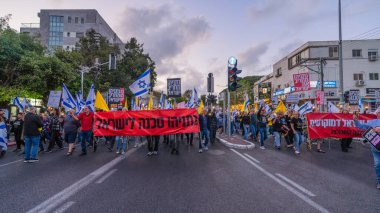 Hayfa, İsrail - 26 Nisan 2025: Çeşitli tabelaları ve bayrakları olan insanlar, savaşın sona ermesi, rehine anlaşmasının tamamlanması ve yeni seçimlerin başlatılması için düzenlenen protesto mitingine katıldılar. Hayfa, İsrail