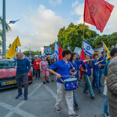Hayfa, İsrail - 3 Mayıs 2025: İnsanlar savaşın sona ermesi, rehine anlaşmasının tamamlanması ve yeni seçimler çağrısında bulunan bir protesto yürüyüşüne (Hashomer Hatzair gençlik hareketi) katılıyor. Hayfa, İsrail