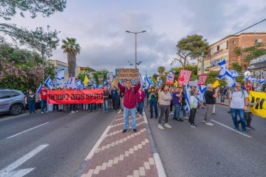 Hayfa, İsrail - 3 Mayıs 2025: Çeşitli tabelaları ve bayrakları olan insanlar, savaşın sona ermesi, rehine anlaşmasının tamamlanması ve yeni seçimler için düzenlenen protesto mitingine katıldılar. Hayfa, İsrail