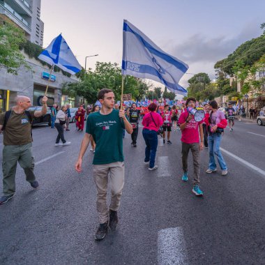 Hayfa, İsrail - 3 Mayıs 2025: Çeşitli tabelaları ve bayrakları olan insanlar, savaşın sona ermesi, rehine anlaşmasının tamamlanması ve yeni seçimler için düzenlenen protesto mitingine katıldılar. Hayfa, İsrail