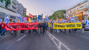 Hayfa, İsrail - 3 Mayıs 2025: Çeşitli tabelaları ve bayrakları olan insanlar, savaşın sona ermesi, rehine anlaşmasının tamamlanması ve yeni seçimler için düzenlenen protesto mitingine katıldılar. Hayfa, İsrail