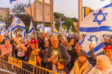 Hayfa, İsrail - 3 Mayıs 2025: Çeşitli tabela ve bayraklara sahip bir grup insan, savaşın sona ermesi, rehine anlaşmasının tamamlanması ve yeni seçimler için düzenlenen protesto mitingine katıldı. Hayfa, İsrail