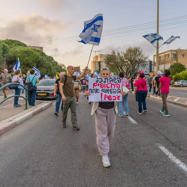 Hayfa, İsrail - 3 Mayıs 2025: Çeşitli tabelaları ve bayrakları olan insanlar, savaşın sona ermesi, rehine anlaşmasının tamamlanması ve yeni seçimler için düzenlenen protesto mitingine katıldılar. Hayfa, İsrail
