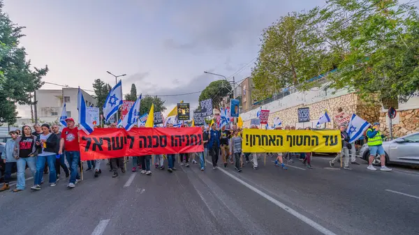 Hayfa, İsrail - 3 Mayıs 2025: Çeşitli tabelaları ve bayrakları olan insanlar, savaşın sona ermesi, rehine anlaşmasının tamamlanması ve yeni seçimler için düzenlenen protesto mitingine katıldılar. Hayfa, İsrail