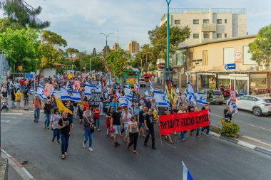 Hayfa, İsrail - 10 Mayıs 2025: Çeşitli tabelaları ve bayrakları olan insanlar, savaşın sona ermesi, rehine anlaşmasının tamamlanması ve yeni seçimlerin başlatılması için düzenlenen protesto mitingine katıldılar. Hayfa, İsrail