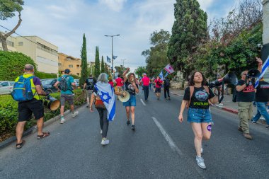 Hayfa, İsrail - 10 Mayıs 2025: Çeşitli tabelaları ve bayrakları olan insanlar, savaşın sona ermesi, rehine anlaşmasının tamamlanması ve yeni seçimlerin başlatılması için düzenlenen protesto mitingine katıldılar. Hayfa, İsrail