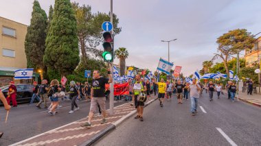 Hayfa, İsrail - 10 Mayıs 2025: Çeşitli tabelaları ve bayrakları olan insanlar, savaşın sona ermesi, rehine anlaşmasının tamamlanması ve yeni seçimlerin başlatılması için düzenlenen protesto mitingine katıldılar. Hayfa, İsrail