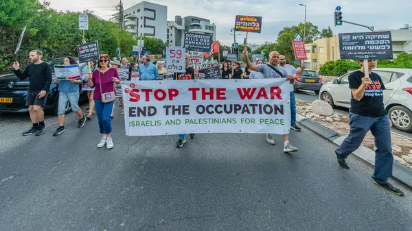 Hayfa, İsrail - 10 Mayıs 2025: İnsanlar çeşitli işaret ve bayraklarla bir protesto yürüyüşüne katılıyor, savaşın sona ermesi ve rehine anlaşmasının tamamlanması çağrısında bulunuyorlar. Hayfa, İsrail
