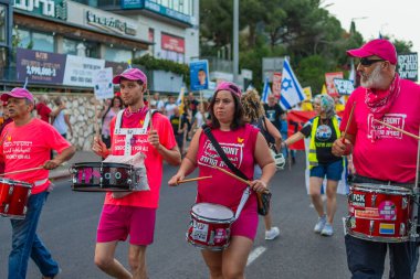 Hayfa, İsrail - 17 Mayıs 2025: İnsanlar savaşın sona ermesi, rehine anlaşmasının tamamlanması ve yeni seçimler çağrısında bulunan bir protesto yürüyüşüne (Pembe Cephe Grubu) katılıyor. Hayfa, İsrail