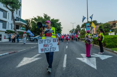 Hayfa, İsrail - 17 Mayıs 2025: Çeşitli tabelaları ve bayrakları olan insanlar, savaşın sona ermesi, rehine anlaşmasının tamamlanması ve yeni seçimlerin başlatılması için düzenlenen protesto mitingine katıldılar. Hayfa, İsrail