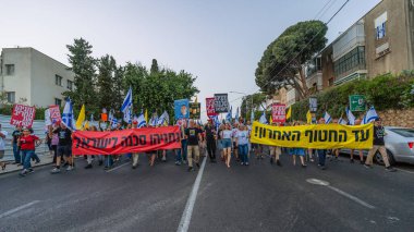 Hayfa, İsrail - 17 Mayıs 2025: Çeşitli tabelaları ve bayrakları olan insanlar, savaşın sona ermesi, rehine anlaşmasının tamamlanması ve yeni seçimlerin başlatılması için düzenlenen protesto mitingine katıldılar. Hayfa, İsrail