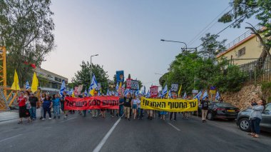 Hayfa, İsrail - 17 Mayıs 2025: Çeşitli tabelaları ve bayrakları olan insanlar, savaşın sona ermesi, rehine anlaşmasının tamamlanması ve yeni seçimlerin başlatılması için düzenlenen protesto mitingine katıldılar. Hayfa, İsrail