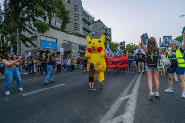Hayfa, İsrail - 17 Mayıs 2025: İnsanlar (Pikachu kostümlü adamla birlikte) savaşın sona ermesi, rehine anlaşmasının tamamlanması ve yeni seçimler çağrısında bulunan bir protesto yürüyüşüne katılıyor. Hayfa, İsrail