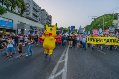 Hayfa, İsrail - 17 Mayıs 2025: İnsanlar (Pikachu kostümlü adamla birlikte) savaşın sona ermesi, rehine anlaşmasının tamamlanması ve yeni seçimler çağrısında bulunan bir protesto yürüyüşüne katılıyor. Hayfa, İsrail