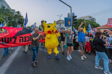 Hayfa, İsrail - 17 Mayıs 2025: İnsanlar (Pikachu kostümlü adamla birlikte) savaşın sona ermesi, rehine anlaşmasının tamamlanması ve yeni seçimler çağrısında bulunan bir protesto yürüyüşüne katılıyor. Hayfa, İsrail