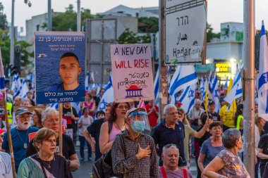 Hayfa, İsrail - 17 Mayıs 2025: Çeşitli tabela ve bayraklara sahip bir grup insan, savaşın sona ermesi, rehine anlaşmasının tamamlanması ve yeni seçimler için düzenlenen protesto mitingine katıldı. Hayfa, İsrail
