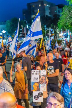 Hayfa, İsrail - 17 Mayıs 2025: Çeşitli tabela ve bayraklara sahip bir grup insan, savaşın sona ermesi, rehine anlaşmasının tamamlanması ve yeni seçimler için düzenlenen protesto mitingine katıldı. Hayfa, İsrail