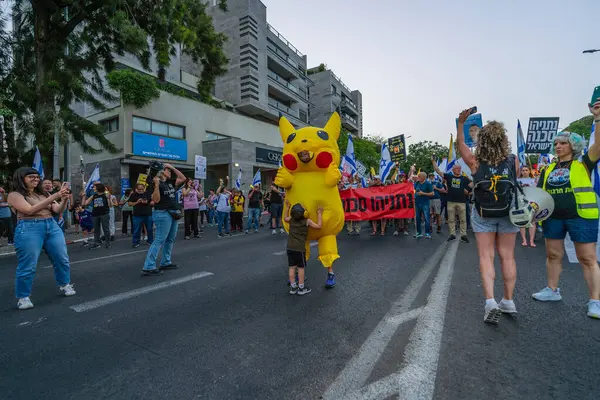 Hayfa, İsrail - 17 Mayıs 2025: İnsanlar (Pikachu kostümlü adamla birlikte) savaşın sona ermesi, rehine anlaşmasının tamamlanması ve yeni seçimler çağrısında bulunan bir protesto yürüyüşüne katılıyor. Hayfa, İsrail