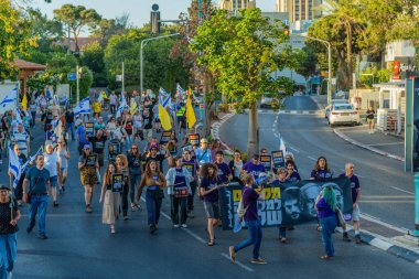 Hayfa, İsrail - 24 Mayıs 2025: Çeşitli tabelaları ve bayrakları olan insanlar, savaşın sona ermesi, rehine anlaşmasının tamamlanması ve yeni seçimlerin başlatılması için düzenlenen protesto mitingine katıldılar. Hayfa, İsrail