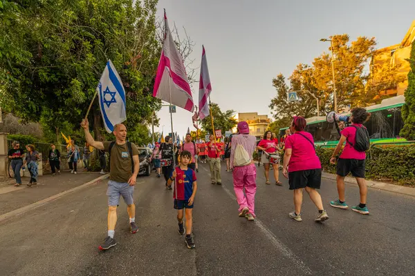 Hayfa, İsrail - 24 Mayıs 2025: İnsanlar savaşın sona ermesi, rehine anlaşmasının tamamlanması ve yeni seçimler çağrısında bulunan bir protesto yürüyüşüne (Pembe Cephe Grubu) katılıyor. Hayfa, İsrail