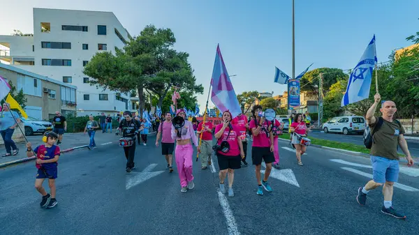 Hayfa, İsrail - 24 Mayıs 2025: İnsanlar savaşın sona ermesi, rehine anlaşmasının tamamlanması ve yeni seçimler çağrısında bulunan bir protesto yürüyüşüne (Pembe Cephe Grubu) katılıyor. Hayfa, İsrail