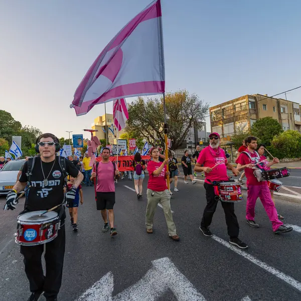 Hayfa, İsrail - 24 Mayıs 2025: İnsanlar savaşın sona ermesi, rehine anlaşmasının tamamlanması ve yeni seçimler çağrısında bulunan bir protesto yürüyüşüne (Pembe Cephe Grubu) katılıyor. Hayfa, İsrail