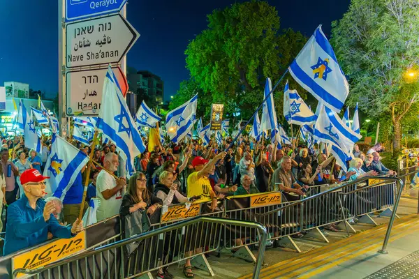 Hayfa, İsrail - 24 Mayıs 2025: Çeşitli tabela ve bayraklara sahip bir grup insan, savaşın sona ermesi, rehine anlaşmasının tamamlanması ve yeni seçimler için düzenlenen protesto mitingine katıldı. Hayfa, İsrail
