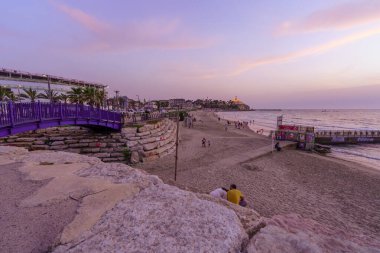 Tel Aviv, İsrail - 16 Mayıs 2025: Sahil yürüyüşü ve eski Jaffa 'nın yerel halk ve ziyaretçilerle gün batımı manzarası. Tel-Aviv-Yafo, İsrail
