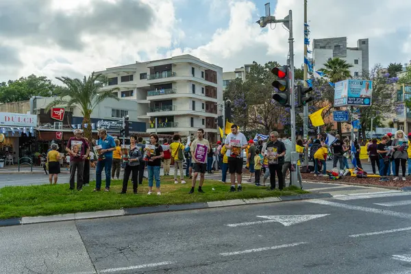 Hayfa, İsrail - 28 Mayıs 2025: İnsanlar, savaşın 600. gününde İsrail 'in Hayfa kentinde, anlaşmanın tamamlanması çağrısında bulunarak, savaşın 600. gününde sarı kurdele, işaret ve bayraklarla protesto ediyorlar.