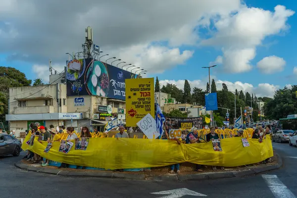 Hayfa, İsrail - 28 Mayıs 2025: İnsanlar, savaşın 600. gününde İsrail 'in Hayfa kentinde, anlaşmanın tamamlanması çağrısında bulunarak, savaşın 600. gününde sarı kurdele, işaret ve bayraklarla protesto ediyorlar.