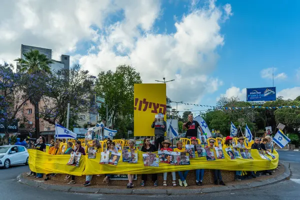 Hayfa, İsrail - 28 Mayıs 2025: İnsanlar, savaşın 600. gününde İsrail 'in Hayfa kentinde, anlaşmanın tamamlanması çağrısında bulunarak, savaşın 600. gününde sarı kurdele, işaret ve bayraklarla protesto ediyorlar.