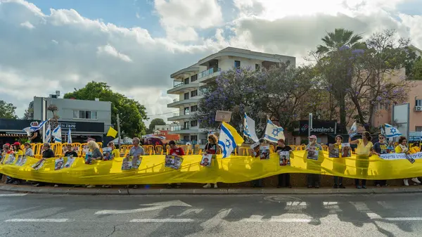 Hayfa, İsrail - 28 Mayıs 2025: İnsanlar, savaşın 600. gününde İsrail 'in Hayfa kentinde, anlaşmanın tamamlanması çağrısında bulunarak, savaşın 600. gününde sarı kurdele, işaret ve bayraklarla protesto ediyorlar.