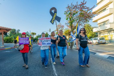 Hayfa, İsrail - 7 Haziran 2025: Çeşitli tabela ve bayraklara sahip insanlar, savaşın sona ermesi, rehine anlaşmasının tamamlanması ve yeni seçimlerin başlatılması için düzenlenen protesto mitingine katıldılar. Hayfa, İsrail