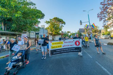 Hayfa, İsrail - Haziran 07, 2025: İnsanlar çeşitli işaret ve bayraklarla bir protesto yürüyüşüne katılıyor, savaşı sona erdirme ve rehine anlaşmasının tamamlanması çağrısında bulunuyorlar. Hayfa, İsrail
