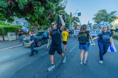 Hayfa, İsrail - 7 Haziran 2025: Çeşitli tabela ve bayraklara sahip insanlar, savaşın sona ermesi, rehine anlaşmasının tamamlanması ve yeni seçimlerin başlatılması için düzenlenen protesto mitingine katıldılar. Hayfa, İsrail