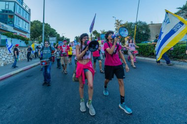 Hayfa, İsrail - Haziran 07, 2025: İnsanlar savaşın sona ermesi, rehine anlaşmasının tamamlanması ve yeni seçimler çağrısında bulunan bir protesto yürüyüşüne (Pembe Cephe Grubu) katılıyor. Hayfa, İsrail