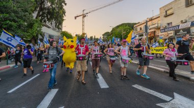 Hayfa, İsrail - Haziran 07, 2025: İnsanlar (Pikachu kostümlü adamla birlikte) savaşın sona ermesi, rehine anlaşmasının tamamlanması ve yeni seçimler çağrısında bulunan bir protesto yürüyüşüne katılıyor. Hayfa, İsrail