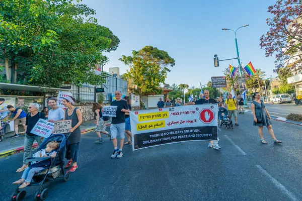 Hayfa, İsrail - Haziran 07, 2025: İnsanlar çeşitli işaret ve bayraklarla bir protesto yürüyüşüne katılıyor, savaşı sona erdirme ve rehine anlaşmasının tamamlanması çağrısında bulunuyorlar. Hayfa, İsrail