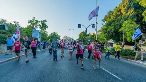 Hayfa, İsrail - Haziran 07, 2025: İnsanlar savaşın sona ermesi, rehine anlaşmasının tamamlanması ve yeni seçimler çağrısında bulunan bir protesto yürüyüşüne (Pembe Cephe Grubu) katılıyor. Hayfa, İsrail