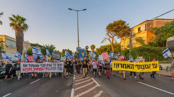 Hayfa, İsrail - 7 Haziran 2025: Çeşitli tabela ve bayraklara sahip insanlar, savaşın sona ermesi, rehine anlaşmasının tamamlanması ve yeni seçimlerin başlatılması için düzenlenen protesto mitingine katıldılar. Hayfa, İsrail