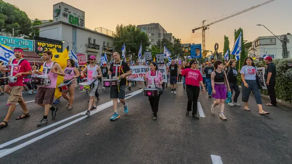 Hayfa, İsrail - Haziran 07, 2025: İnsanlar (Pikachu kostümlü adamla birlikte) savaşın sona ermesi, rehine anlaşmasının tamamlanması ve yeni seçimler çağrısında bulunan bir protesto yürüyüşüne katılıyor. Hayfa, İsrail