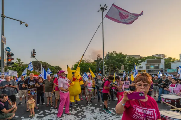 Hayfa, İsrail - Haziran 07, 2025: Davul çemberi, sembolik Katar parasıyla ve Hayfa, İsrail 'deki bir protesto mitinginin bir parçası olan Pikachu kostümlü adamla
