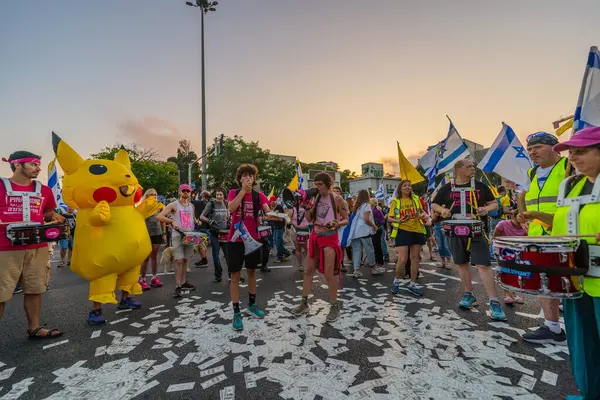 Hayfa, İsrail - Haziran 07, 2025: Davul çemberi, sembolik Katar parasıyla ve Hayfa, İsrail 'deki bir protesto mitinginin bir parçası olan Pikachu kostümlü adamla