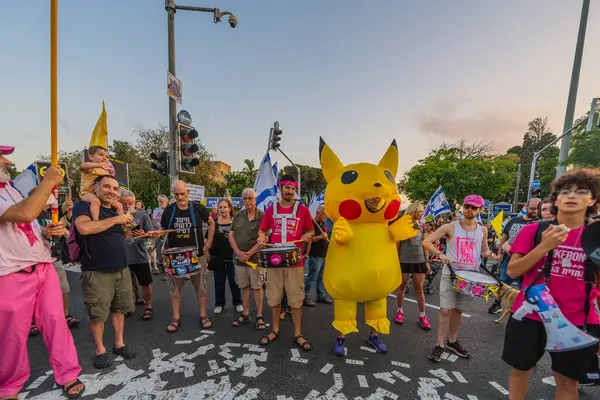 Hayfa, İsrail - Haziran 07, 2025: Davul çemberi, sembolik Katar parasıyla ve Hayfa, İsrail 'deki bir protesto mitinginin bir parçası olan Pikachu kostümlü adamla